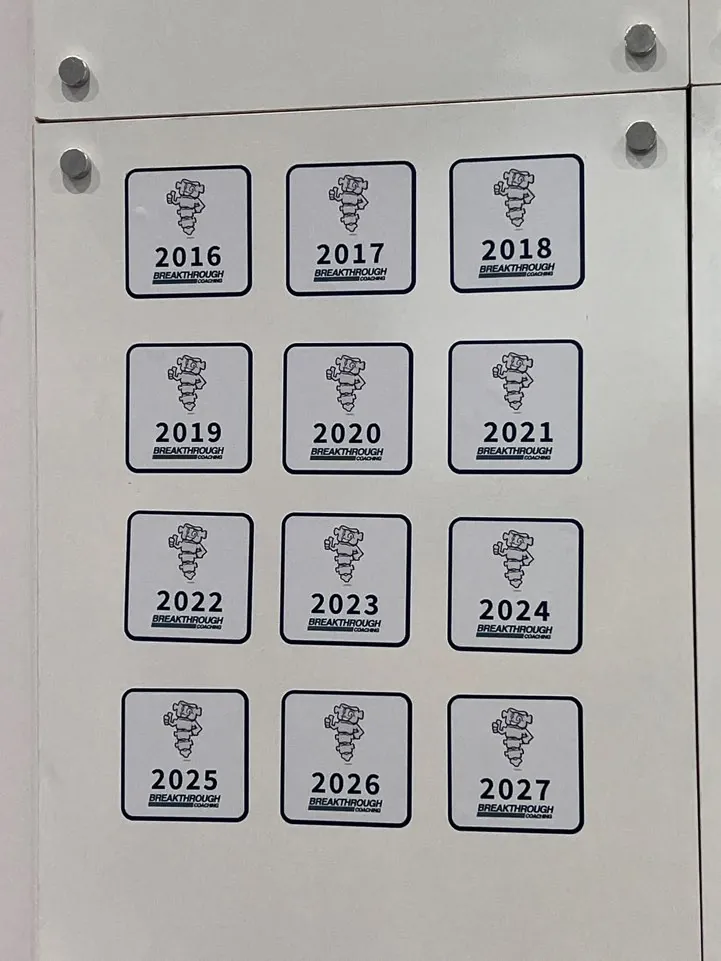 부스 벽에 2016년부터 2027년까지 배지가 붙어 있습니다.